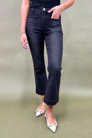 Person wearing dark blue jeans and white shoes on a plain background