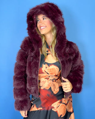 Burgundy faux fur cropped jacket with plush textured fabric, oversized collar, long sleeves, and gold zipper closure.