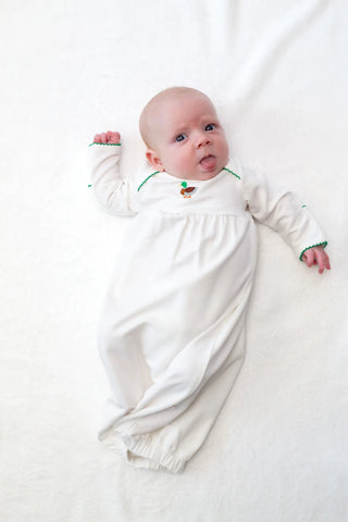 Baby in a white outfit with green trim on a white background