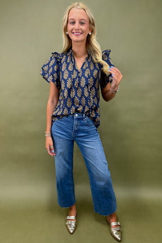 Woman wearing a blue floral blouse and jeans against a green background