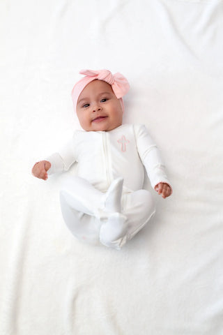 Baby in a white outfit with a pink bunny hat on a white background