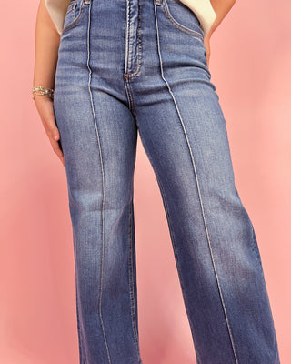 Blue jeans worn by a person on a pink background