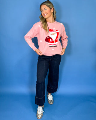 Pink Christmas knit sweater with Santa Claus graphic, white snowflake accents, crew neckline, long sleeves, and ribbed trim.