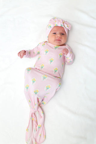 Newborn baby wrapped in a pink floral swaddle blanket and hat on a white background