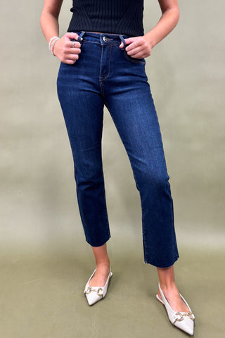 Person wearing blue jeans and white shoes on a plain background