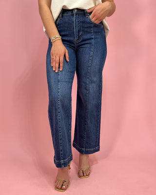 Person wearing blue jeans against a pink background