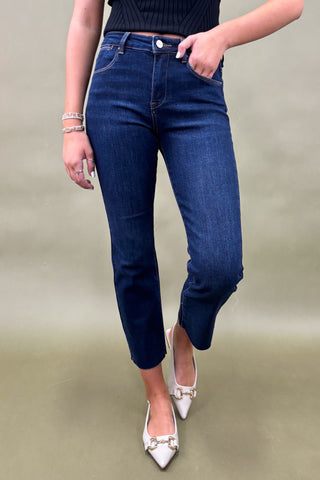 Person wearing blue jeans and white shoes on a plain background