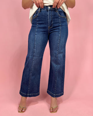 Person wearing blue jeans on a pink background