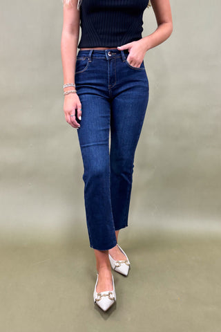 Person wearing blue jeans and a black top on a plain background