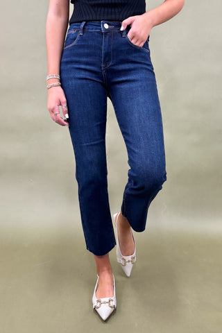 Person wearing blue jeans and white shoes on a plain background