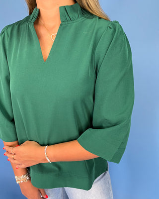 Green blouse worn by a person against a blue background