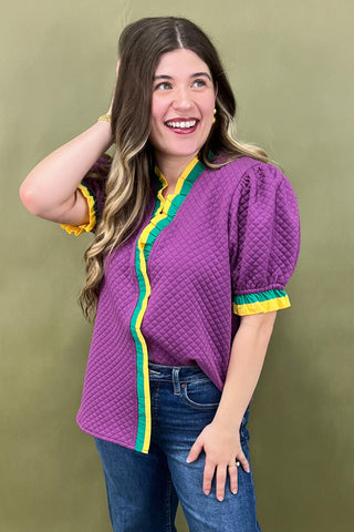 Woman wearing a purple quilted jacket with colorful trim against a green background