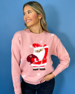 Pink Christmas knit sweater with Santa Claus graphic, white snowflake accents, crew neckline, long sleeves, and ribbed trim.