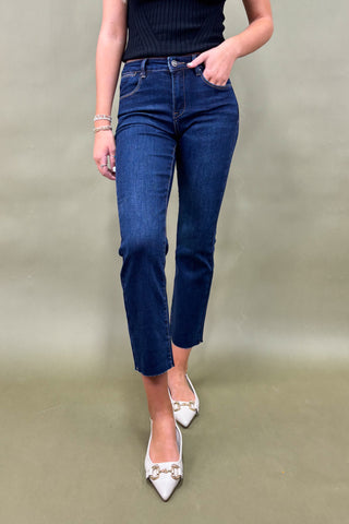 Person wearing blue jeans and white shoes on a plain background