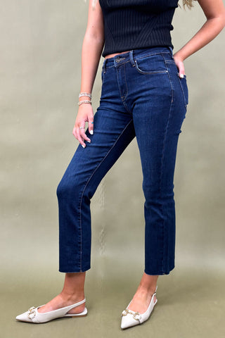 Person wearing blue jeans and white shoes on a plain background