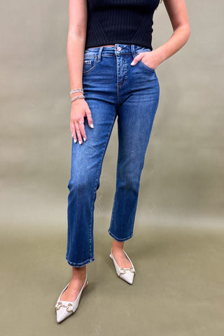 Person wearing blue jeans and a black top against a green background