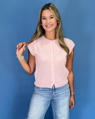Woman wearing a pink blouse and blue jeans against a blue background