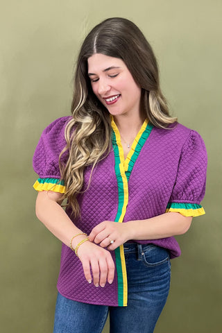 Woman wearing a purple top with green and yellow trim against a green background