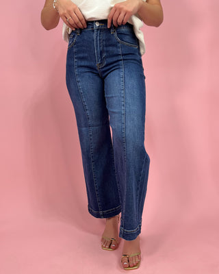Person wearing blue jeans on a pink background