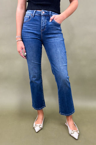 Person wearing blue jeans and white shoes on a plain background