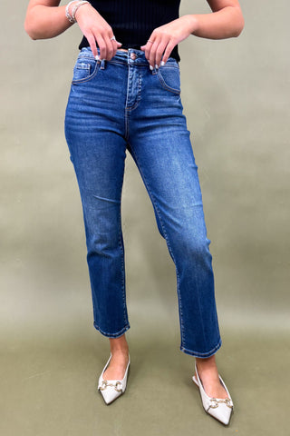 Person wearing blue jeans and white shoes on a plain background