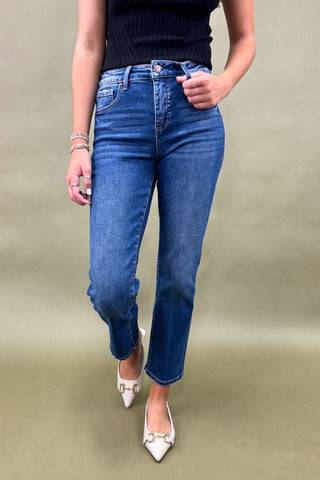 Person wearing blue jeans and a black top on a beige background