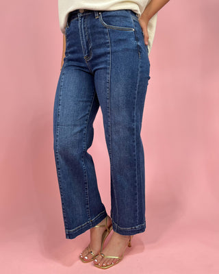 Person wearing blue jeans on a pink background