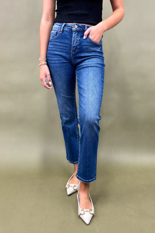 Person wearing blue jeans and white shoes on a plain background