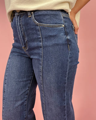 Person wearing blue jeans against a pink background