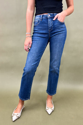 Person wearing blue jeans and white shoes on a plain background