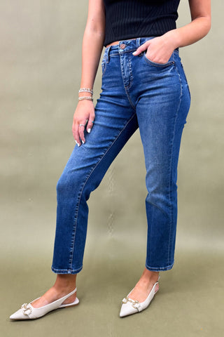 Person wearing blue jeans and a dark top on a plain background