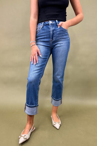 Person wearing blue jeans and a black top on a green background