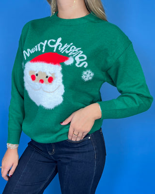 Green Christmas knit sweater with Merry Christmas lettering, fuzzy Santa face graphic, snowflake accents, and ribbed trim.