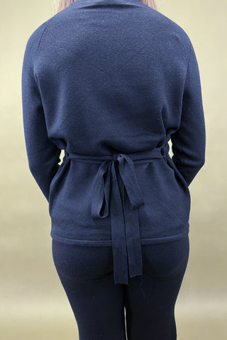 Navy blue cardigan with a tie waist worn by a person on a beige background