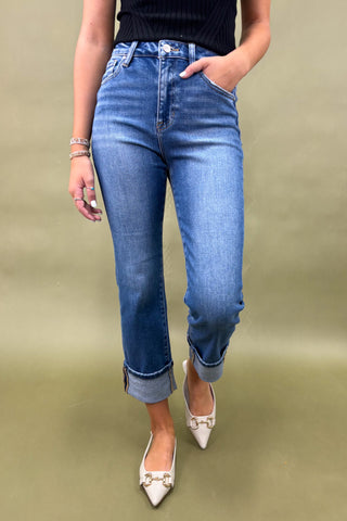 Person wearing blue jeans and white shoes on a green background