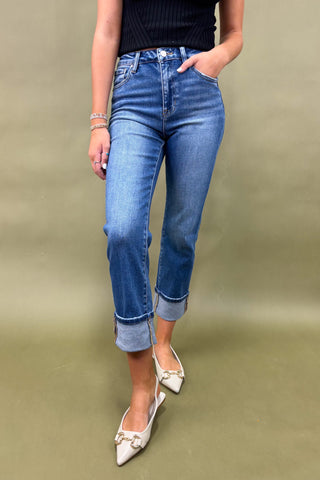 Person wearing blue jeans and white shoes on a green background