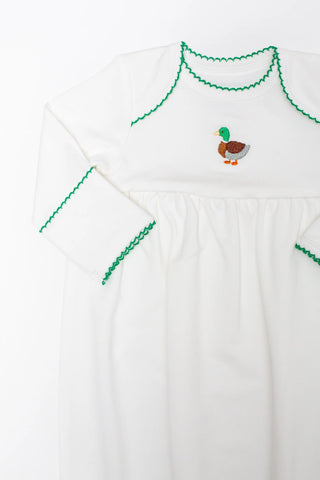 White dress with green embroidery and a small duck design on a white background