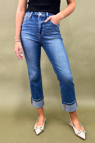 Person wearing blue jeans and white shoes on a green background