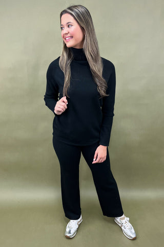Woman wearing a black outfit with white sneakers on a beige background