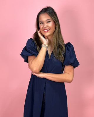 Woman wearing a navy blue dress against a pink background