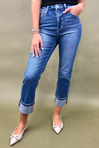 Person wearing blue jeans and white shoes on a beige background