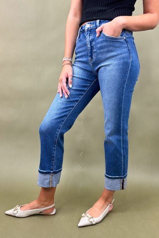 Person wearing blue jeans and white shoes on a plain background