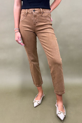 Person wearing tan pants and white shoes on a plain background
