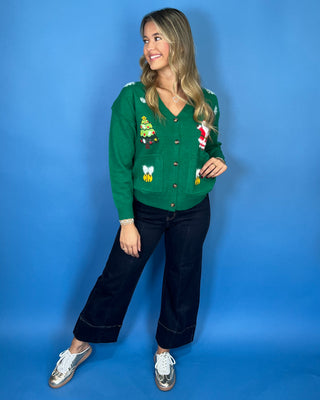 Green Christmas knit cardigan with V-neckline, button front, festive Santa and Christmas tree designs, and front pockets.