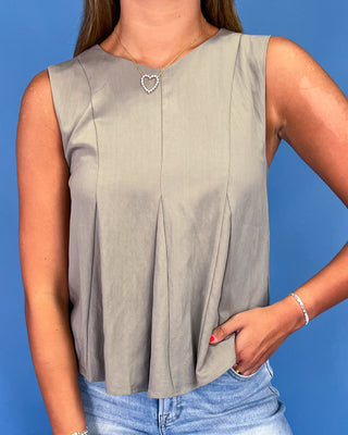 Woman wearing a sleeveless beige top against a blue background