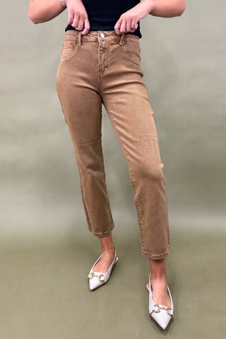 Person wearing brown pants and white shoes on a plain background