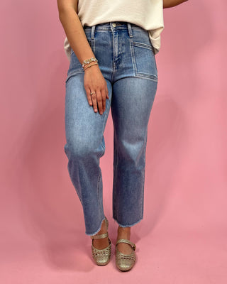 Person wearing blue jeans and a white top on a pink background