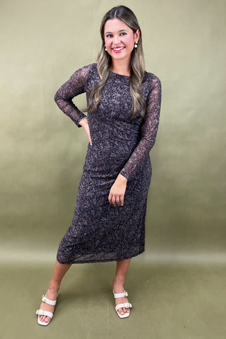 Woman wearing a black lace dress against a green background