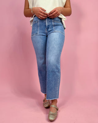 Person wearing blue jeans on a pink background