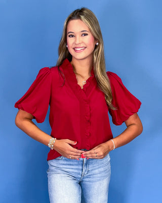 Woman wearing a red blouse with puffed sleeves against a blue background